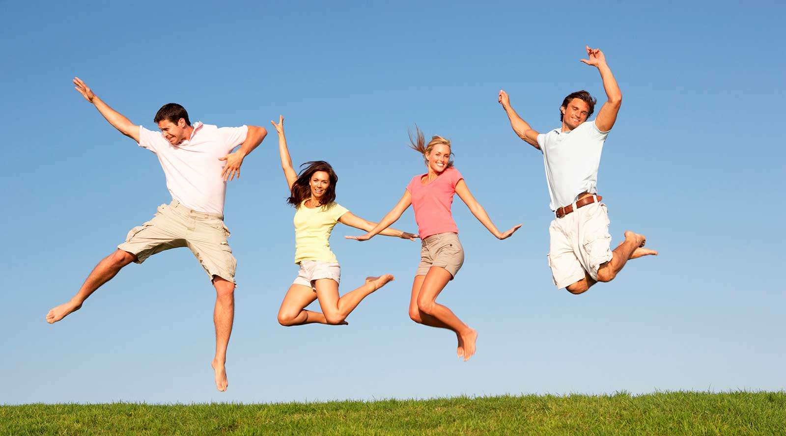 People jumping for joy on a grassy knoll