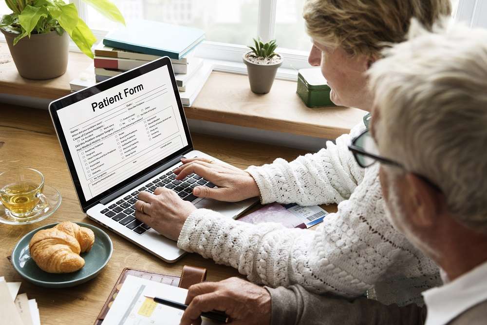 Elderly couple filling in a patient form on a laptop