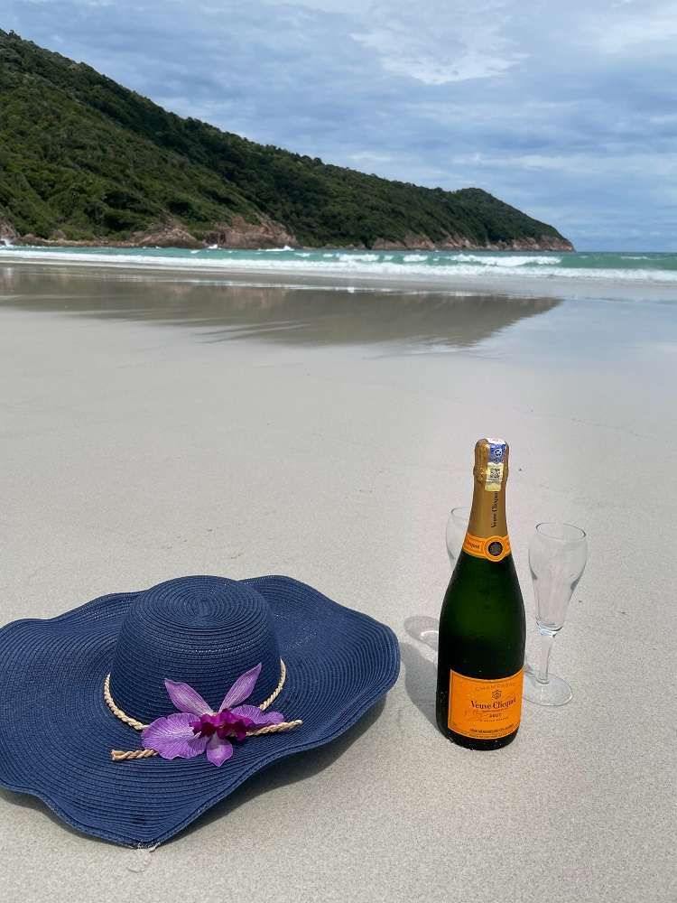 Bottle of champagne and hat on the beach