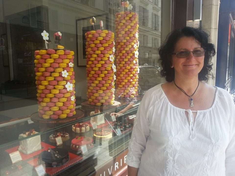 Maria with a big smile in front of a French patisserie display