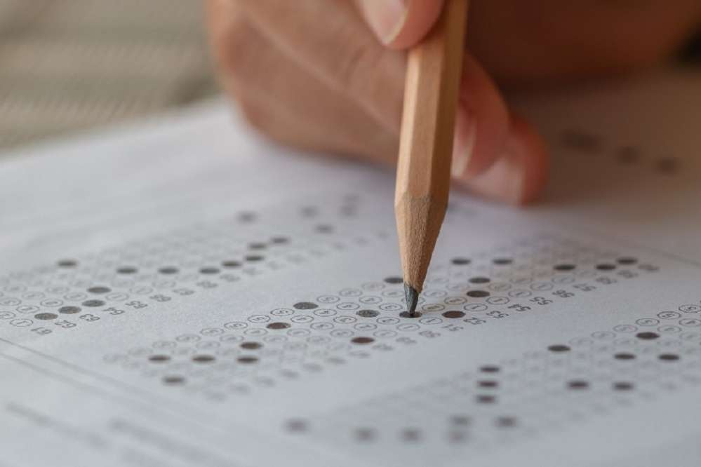 Student hand filling in a test with a pencil
