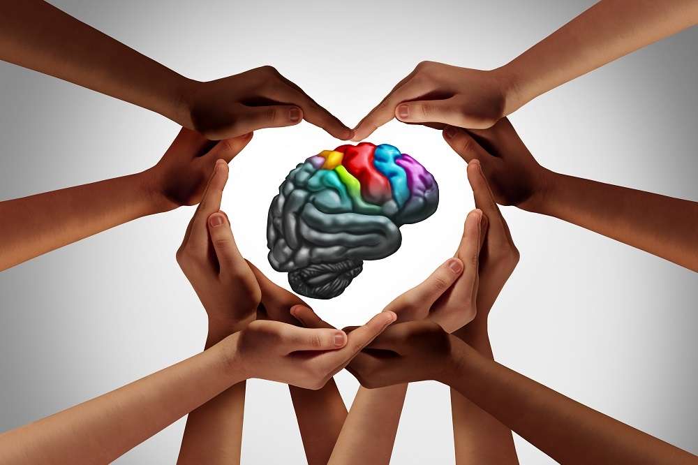 Many hands encircling a human brain representing mental health