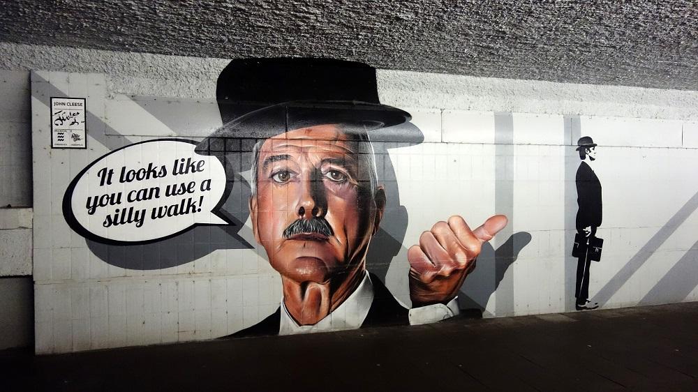 A subway walkway with an image of Monty Pythons John Cleese with a speech bubble saying "It Looks Like You Can Use A Silly Walk"