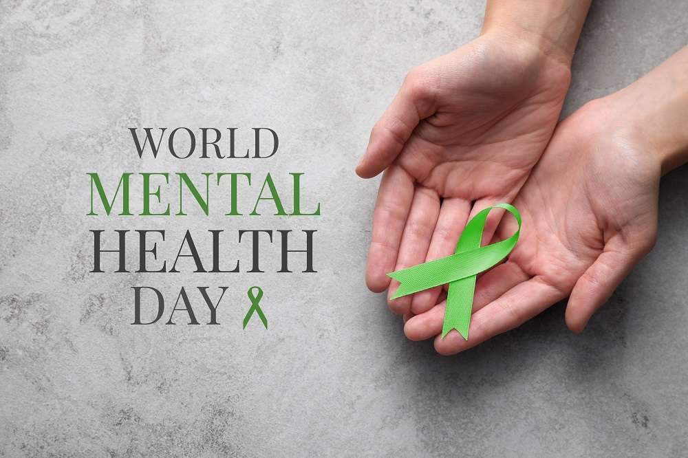 A woman holding a green ribbon representing World Mental Health Day