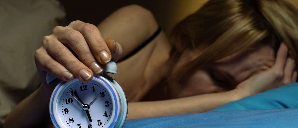 Woman in bed turning off an alarm and cannot wake up in the morning after poor sleep