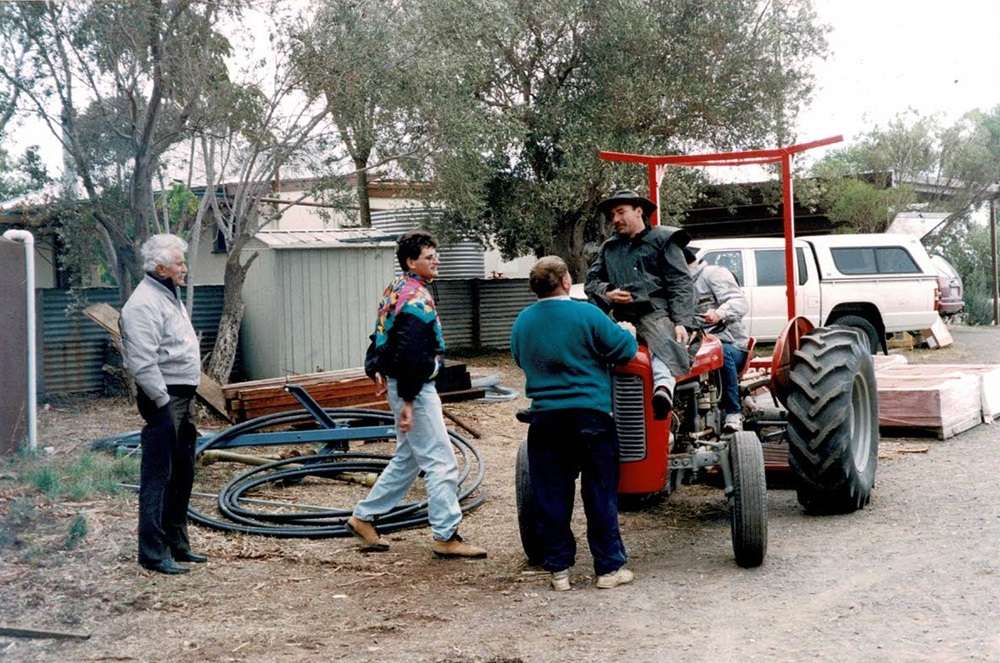 Four men on a farm around a red tractor