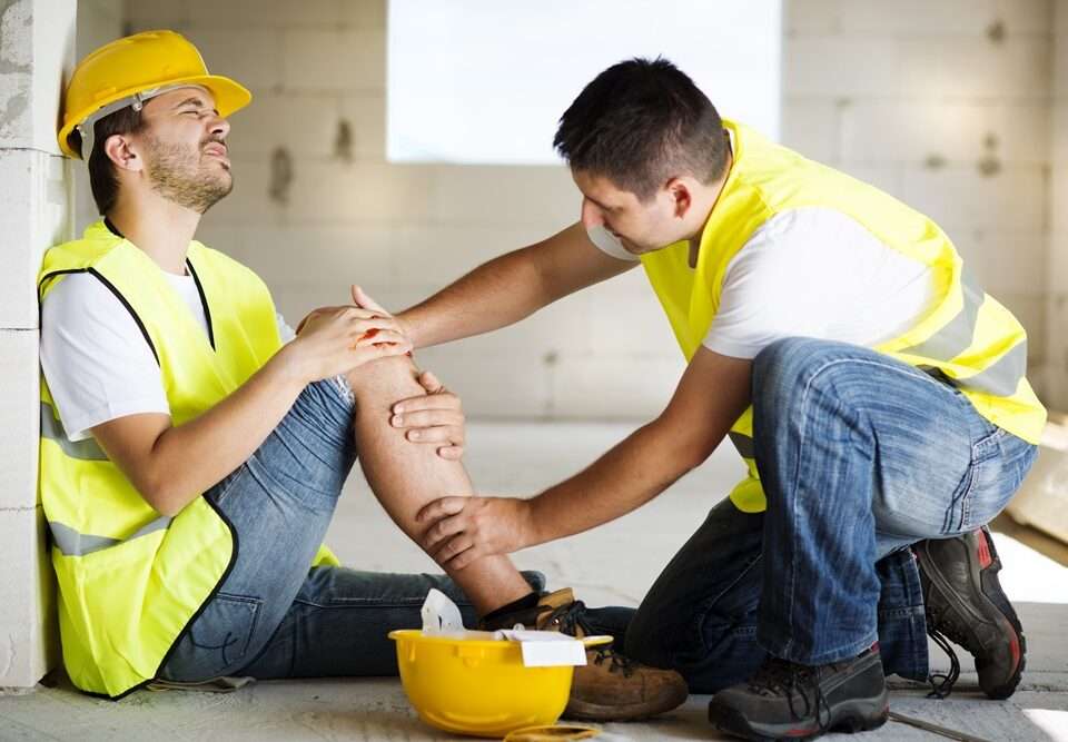 Construction worker being attended to by another person after an accident
