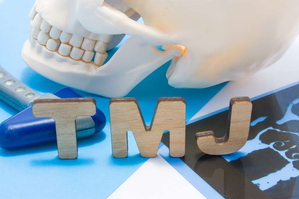 A human skeleton skull showing the teeth and TMJ letters in front