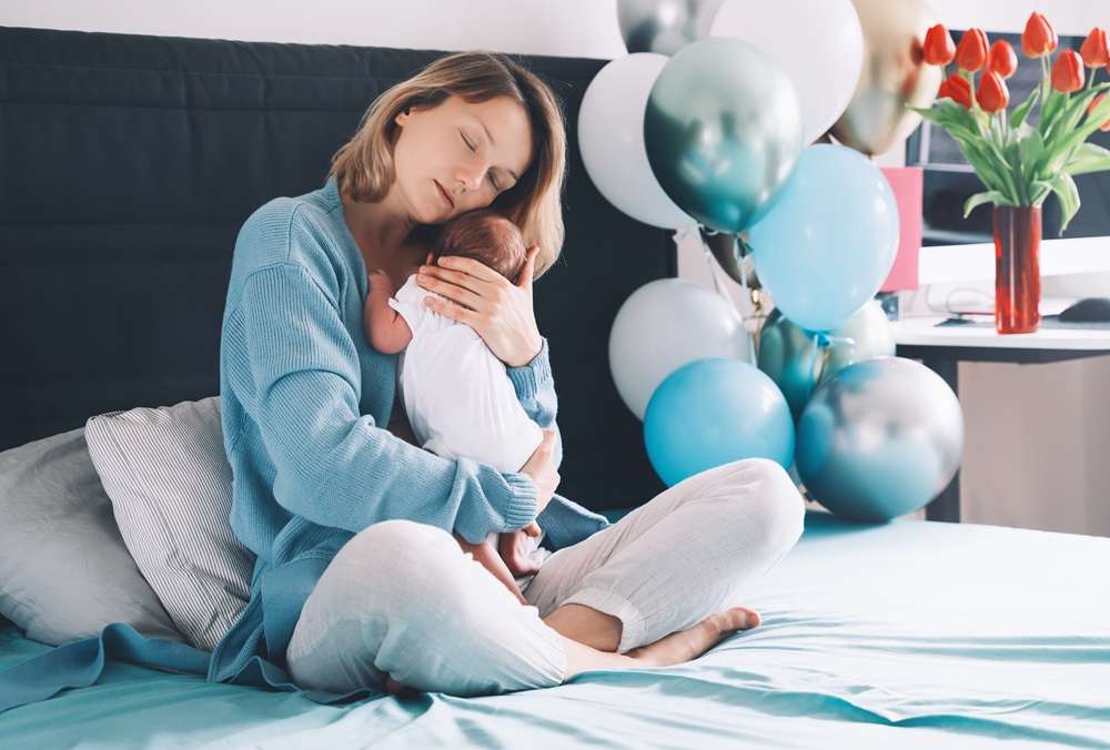 Mother sitting on a bed with her new baby