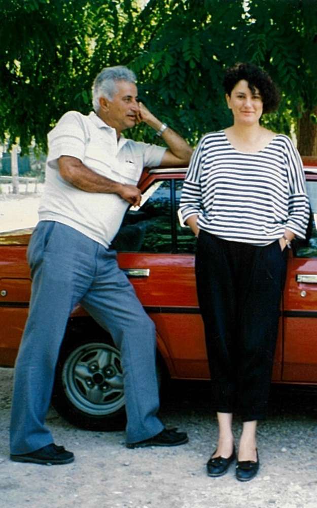 Maria and Father standing in front of a red car