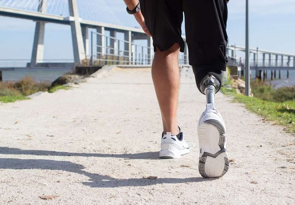 View of a man legs walking towards a jetty. One leg is a prosthetic.