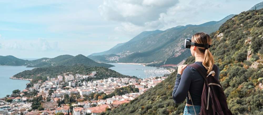 A woman wearing a VR glasses viewing a lake and island with housing