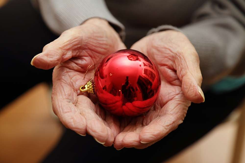 A red Christmas bauble in held in human hands