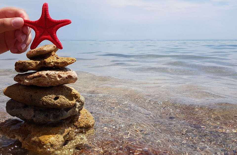 Christmas tree made from rocks by the seas shore with a star fish on top