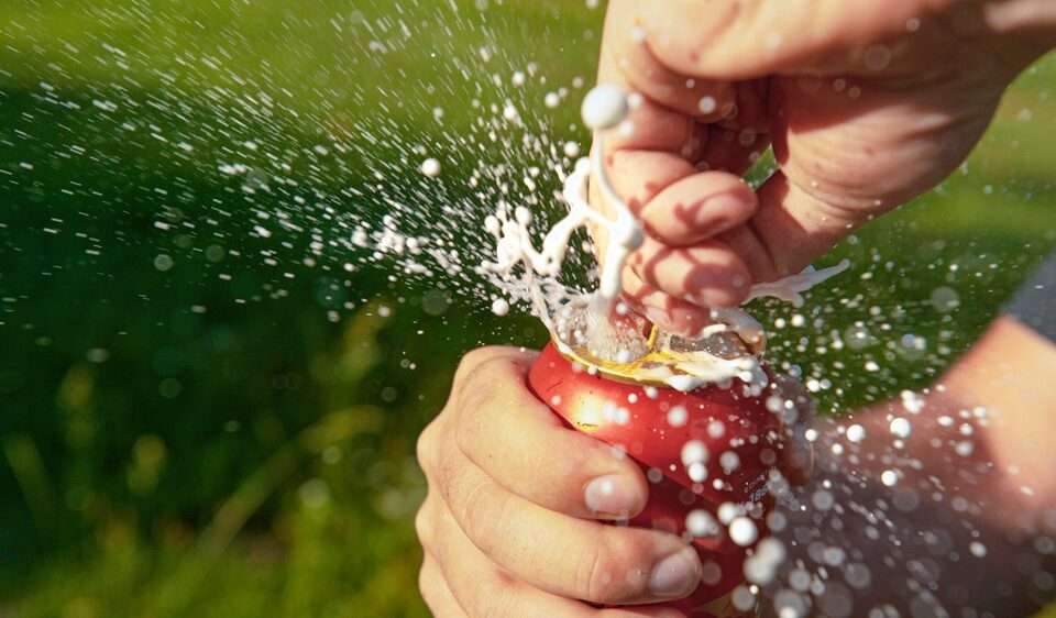 A man's hands opening a can of soft drink and it fizzes out