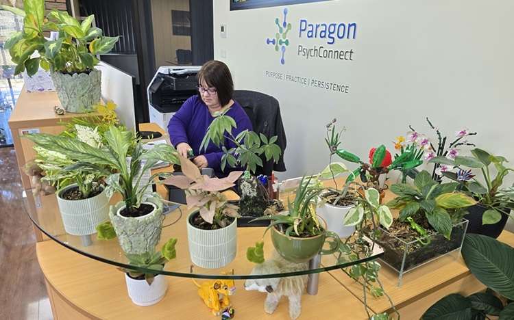 Angela at her desk surrounded by her plants and lego