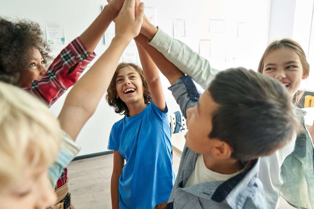 Several children in a circle high fiving each other