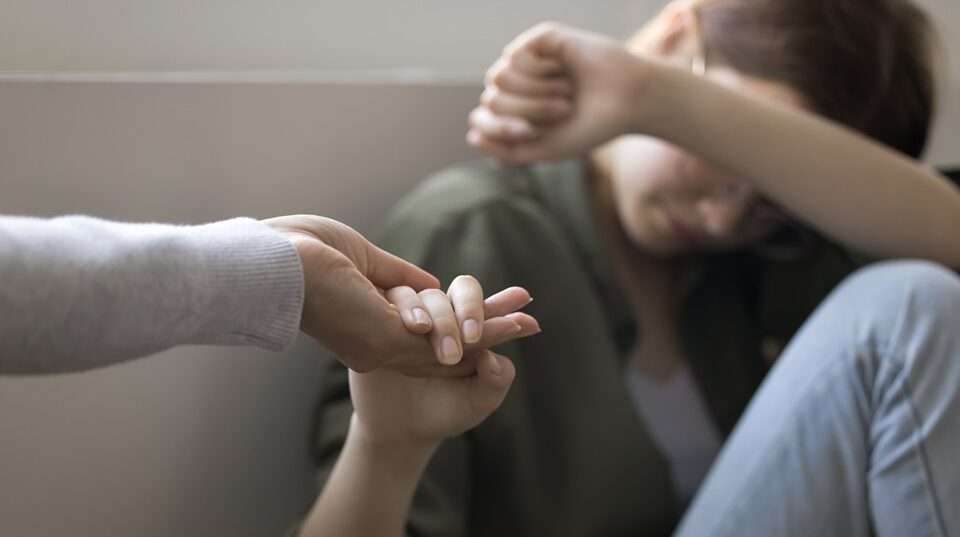 A depressed teenage girl taking hand of mother