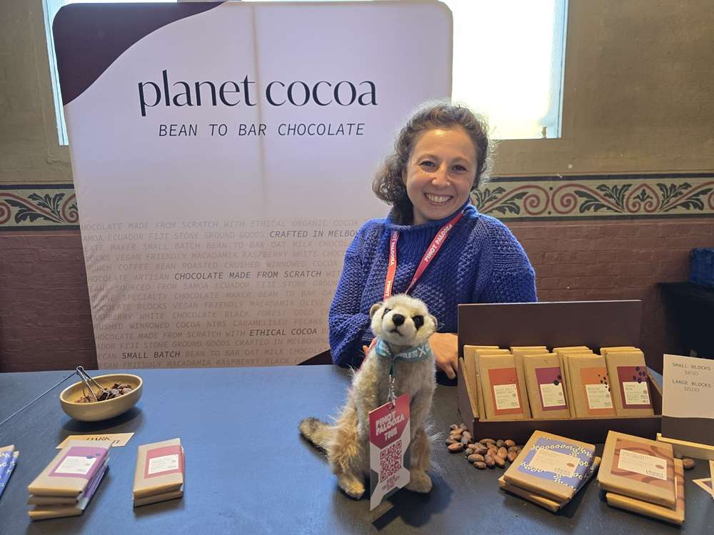 Pinot Palooza Planet Cocoa 2025 - Paragon PsychConnect A Planet Cocoa chocolate display with Brucee the Meerkat and a woman serving