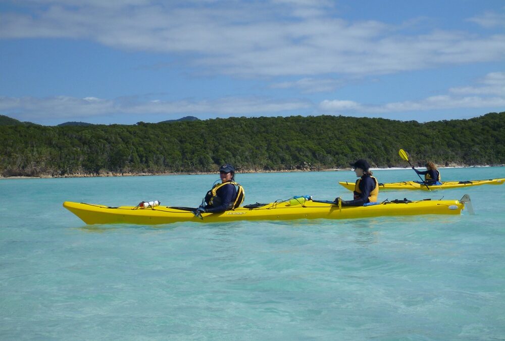 You can find stillness even in active moments – just sit in the kayak and listen to the sounds of nature - Paragon PsychConnect Maria and another person in a double yellow kayak in the Whitsundays