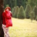 Woman with Pillow - Paragon PsychConnect A woman holding a red pillow standing next to a tree