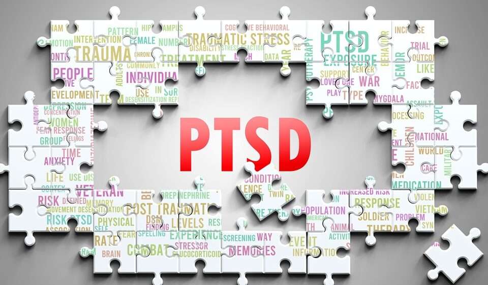 The word PTSD surrounded by with mental health words related to PTSD on jigsaw pieces