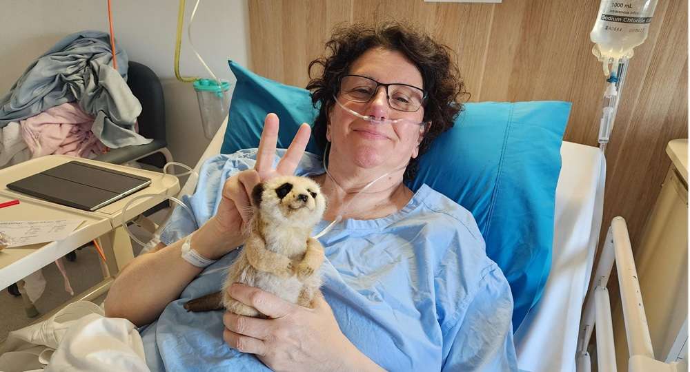 Maria in Hospital - Paragon PsychConnect Maria lying in a hospital bed with Brucee the meerkat
