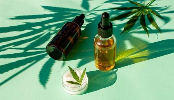 A bottle of medical cannabis oil on a green background with cannabis leaves