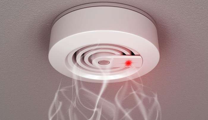 A ceiling smoke alarm with smoke coming out of it